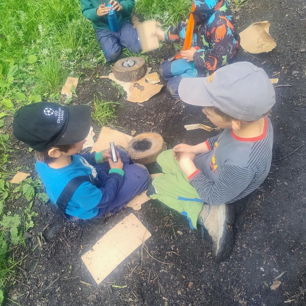 Kinder werken konzentriert mit Holzstämmen und Werkzeug